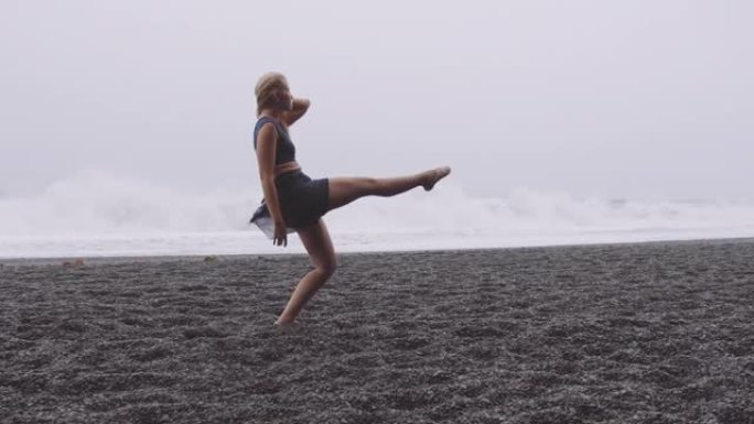 穿着芭蕾舞鞋的女士在黑色沙滩与奇妙的波浪背景