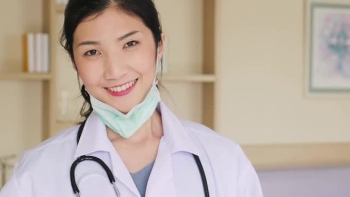 亚洲女医生在完成检查工作后取下保护性手术面罩。穿着医生礼服的护理人员的肖像在医院脱下口罩。健康职业中