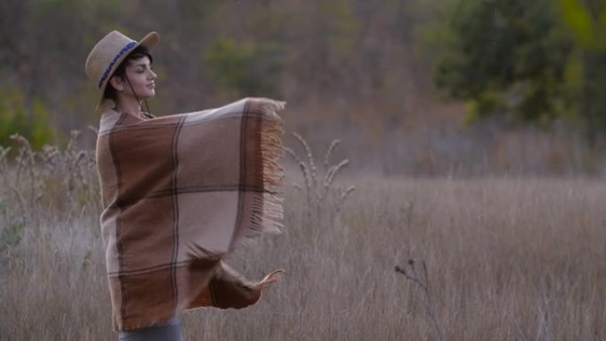 穿着草帽的迷人短发高加索时髦女孩旋转乐趣，用温暖舒适的方格羊毛格子包裹自己。晚上天气变凉了。4K 5
