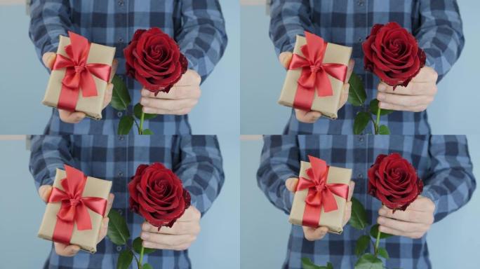 男人正在向相机展示礼物盒和红玫瑰。手拿情人节或国际妇女节的礼物。男送礼盒绑红蝴蝶结，特写