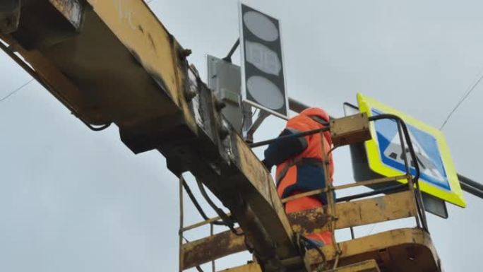 电梯托架中的一名工人修理LED交通信号灯。路标。LED技术。行人过路标志