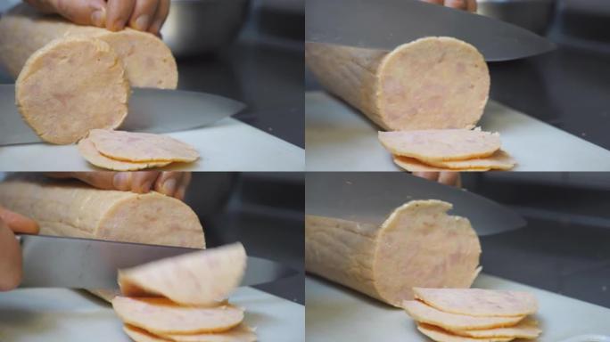在烹饪时，用小刀将男性的手在塑料砧板上切成香肠片。厨师在厨房餐厅准备烹饪披萨的配料。慢动作