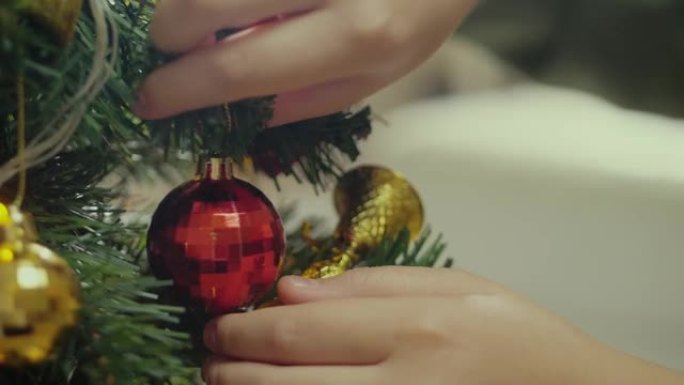 孩子的手在家里的夜晚装饰圣诞树，假期的概念。
