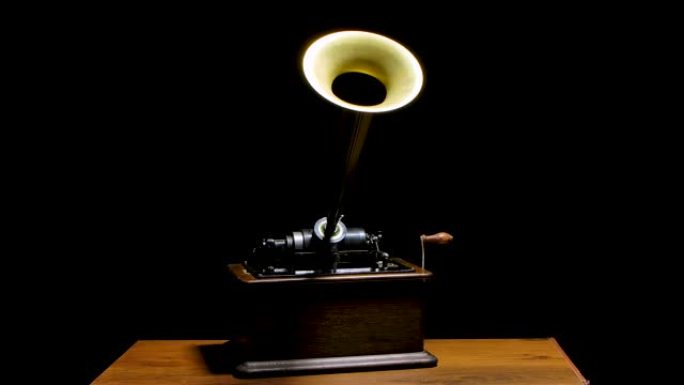 经典的爱迪生留声机在黑暗的工作室的木桌上。复古复古机器重现听音乐的声音。慢动作