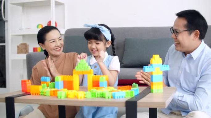 父母与女儿一起玩塑料砖