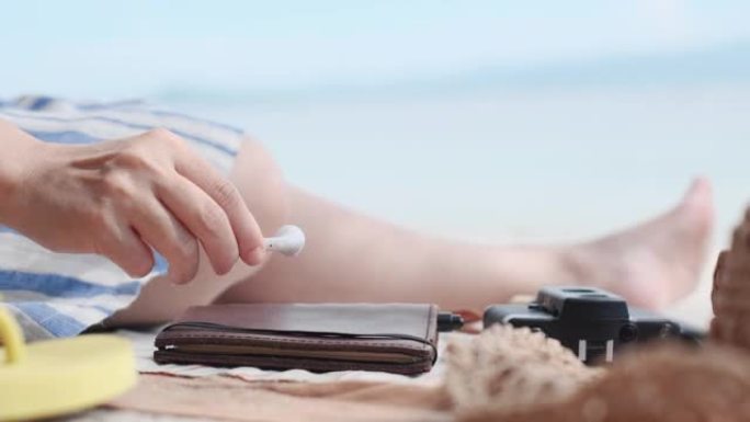 暑假时间关闭快乐亚洲女人用耳机听音乐连接到海滩手机