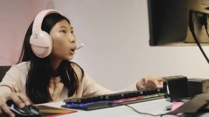 亚洲女孩使用耳机和电脑在家玩带发光二极管灯的在线游戏，一代阿尔法生活方式概念