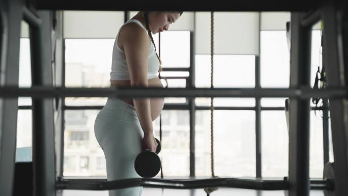 怀孕的现代女性在健身房锻炼身体撸铁