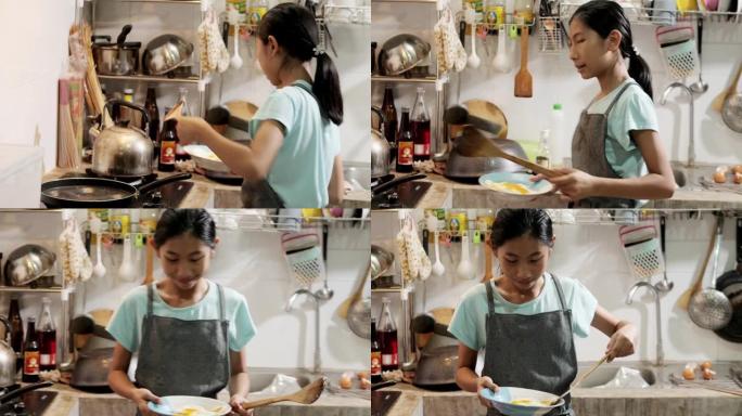 快乐的亚洲女孩在家里的厨房里穿着围裙和烹饪煎蛋，生活方式的概念。