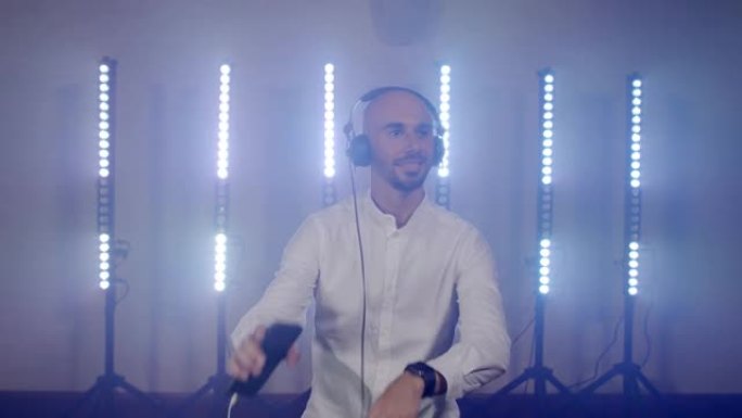 带耳机的精力充沛的光头男人的现场DJ表演，从手机上听音乐跳舞