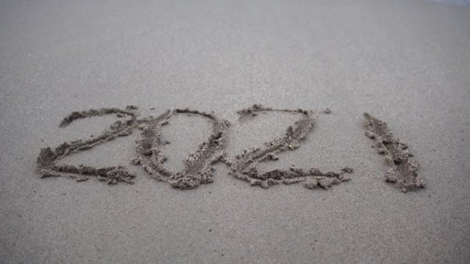 数字2021在沙子里。新年快乐2022来了。新年2022即将到来的概念-沙滩上的数字。2021年在日