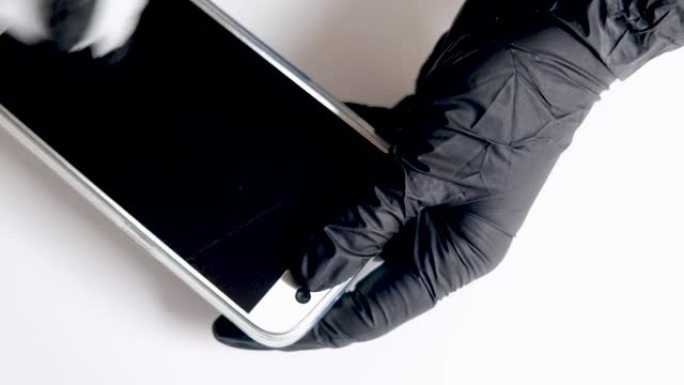 用黑色手套蘸湿纸巾清洁智能手机屏幕或手机显示屏。