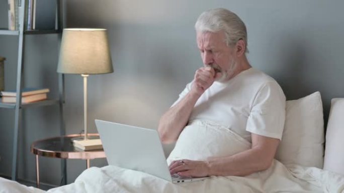 笔记本电脑在床上咳嗽的老人