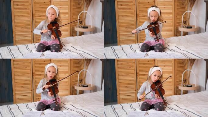 学龄前女孩在家床上拉小提琴
