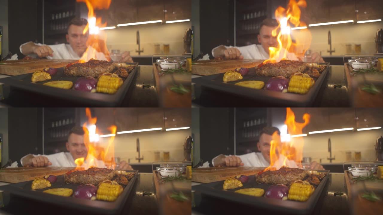 厨师看烧烤现代厨房的肉牛排特写。用火餐厅准备火焰烤盘。烤架煎锅里的火焰。做美味的食物。在菜肴上加工餐