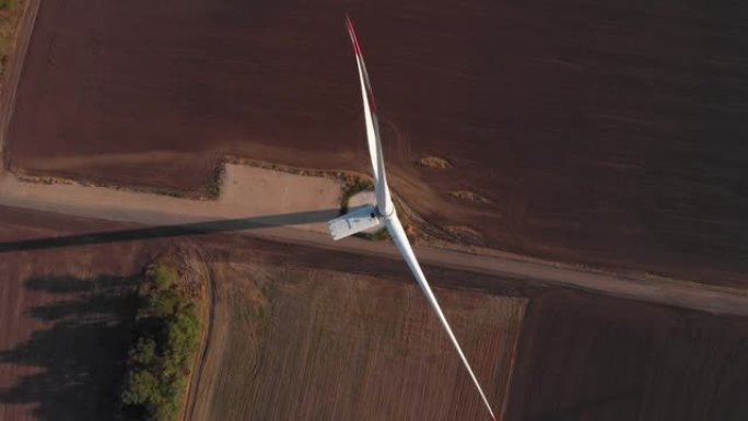 日落时，风力涡轮机发电厂的封闭转子上方的电影式俯视图投射了长长的阴影。绿色能源航拍4k农业领域