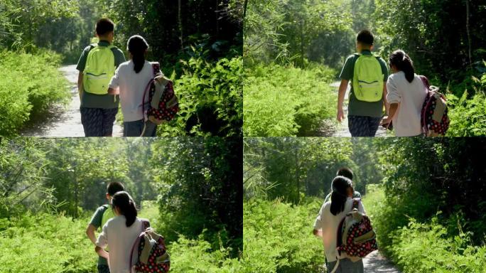 快乐的亚洲男孩和他的妹妹带着背包在阳光明媚的日子一起走在森林里，生活方式的概念。