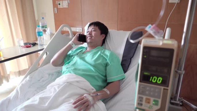 男性亚裔患者在医院病房使用电话。