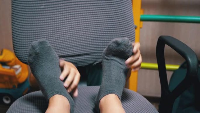 卧室扶手椅上的儿童手在灰色袜子中挠痒痒的女性腿