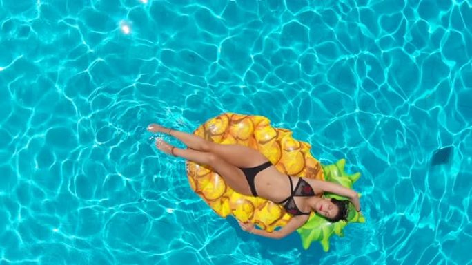 美女在菠萝形床垫上放松的鸟瞰图