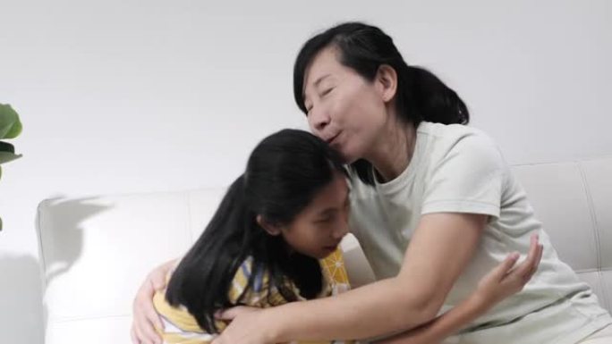 快乐的亚洲女孩在家坐在一起拥抱母亲，生活方式理念。