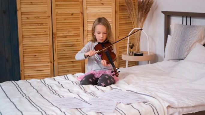小女孩坐在床上拉小提琴