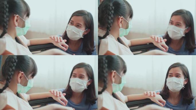 亚洲母亲在医院的康复室里用轮椅照顾孩子。妈妈和孩子戴口罩，以防止COVID病毒感染。新的正常生活方式