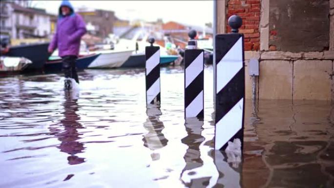 穿着特殊橡胶靴的男子沿着被水淹没的街道行走