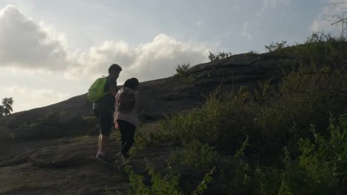 背包客儿童的轮廓与日出背景，生活方式概念一起走到山顶。