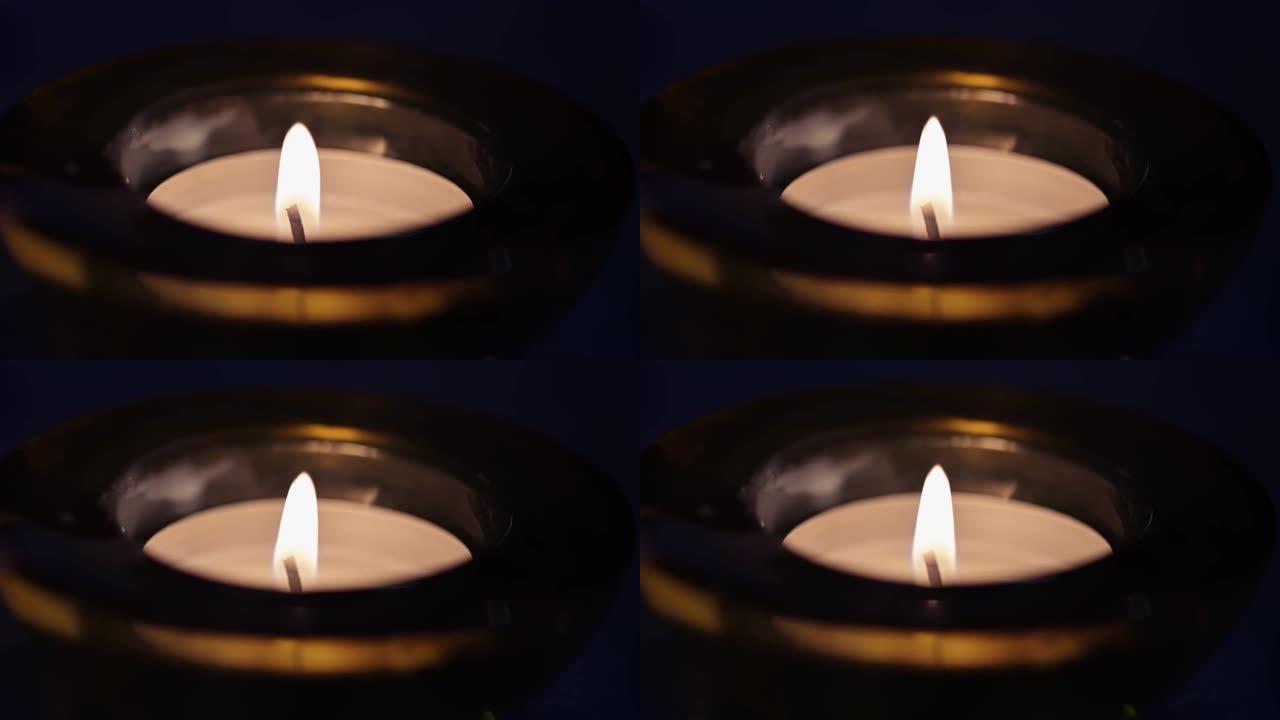 一根蜡烛在低调的灯光下燃烧。蜡烛芯的特写视图。