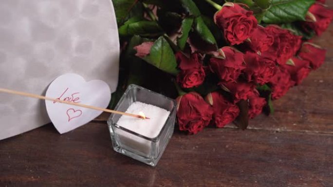 蜡烛站在一个大盒子的推车中，呈心形和一束红玫瑰的形式。点燃火。情人节