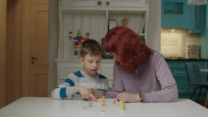 自闭症治疗师教自闭症儿童。自闭症的男生和妈妈一起学习动物。家庭自闭症谱系障碍教育。