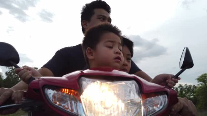 爸爸带着他的两个儿子在乡村公路上开着摩托车