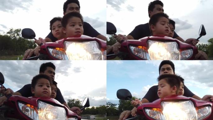 爸爸带着他的两个儿子在乡村公路上开着摩托车
