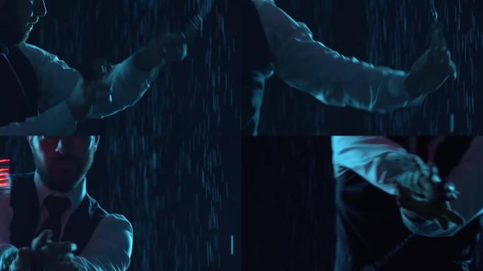 一位专业的马戏团艺术家用发光的手榴弹表演技巧。时尚的男人在黑暗的工作室背景下在雨中表演。戴帽子的艺术