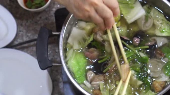 特写中式清汤火锅海鲜蔬菜用筷子和手吃