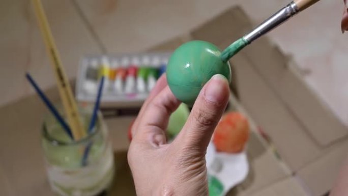 人们用毛笔画绿色复活节彩蛋工艺品。