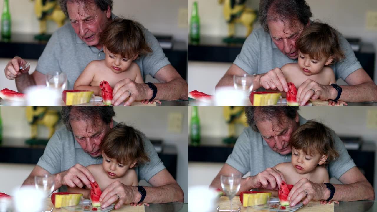 爷爷腿上的小孙子男孩吃西瓜。婴儿拒绝食物，不想吃东西