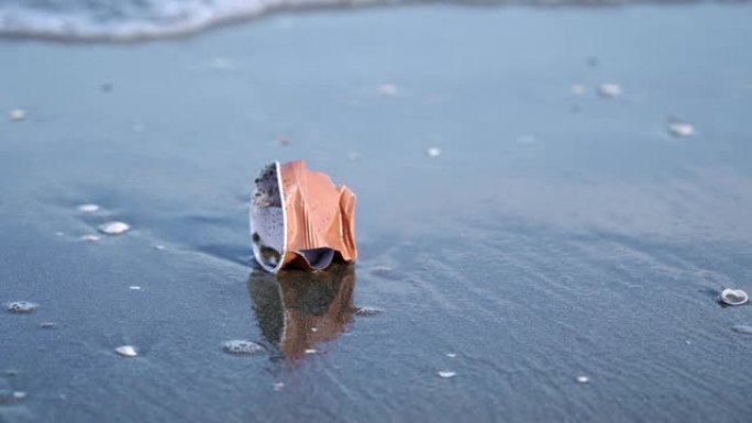 海滩沙滩上皱巴巴的塑料杯，抵御海浪