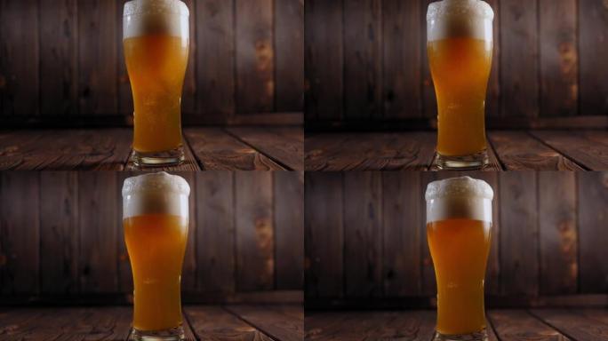 调酒师将清淡的新鲜冰镇啤酒倒入木制背景上的玻璃杯中。
