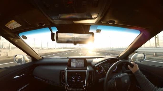 夫妇在公路旅行中，车辆视点驾驶到日落，驾驶员视点的宽图像视图