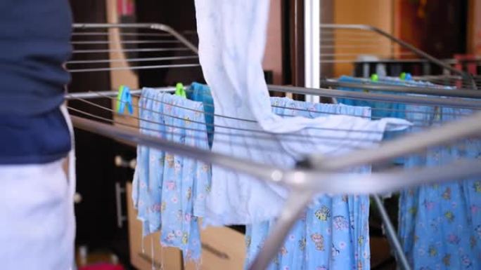 男人把儿童衣服挂在家里的晾衣机上。
