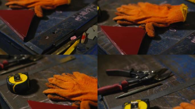 金属桌子上工程工具的跟踪镜头。防护手套、卷尺、铅笔、金属剪刀和金属片。在制造锡制品的车间工作