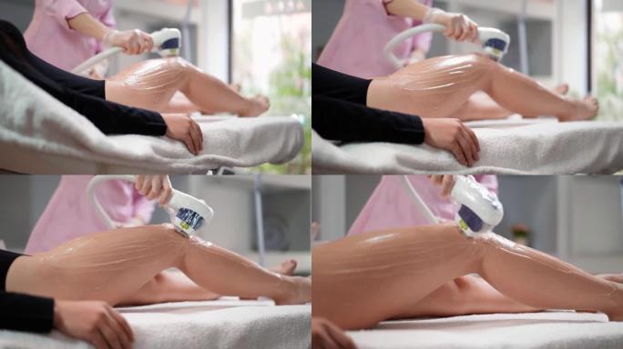 女美容师做激光脱毛苗条的腿美丽性感的女人是躺在美容沙龙的医疗沙发上。宇宙学，脱毛和水疗概念。身体保健