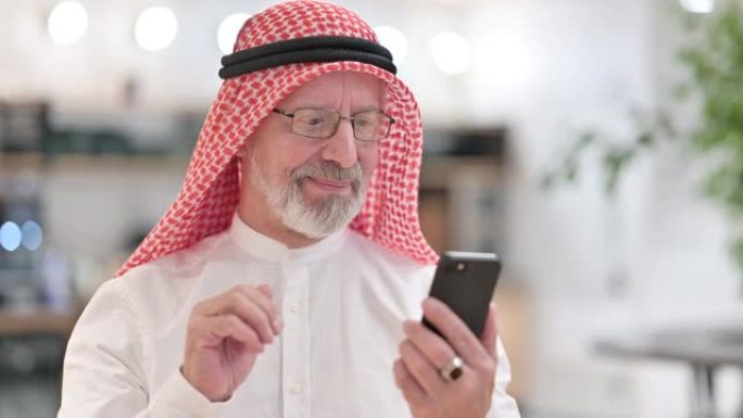 阿拉伯老商人在智能手机上庆祝成功