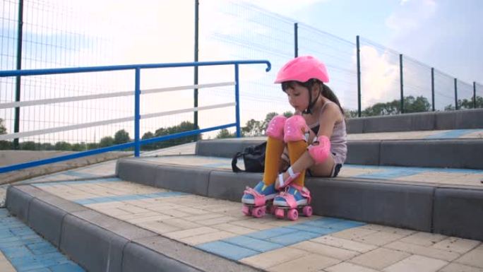 小女孩第一次来到轮滑公园学习轮滑。学龄前的漂亮孩子穿着安全套装，穿上粉色旱冰鞋，4k慢动作50 FP