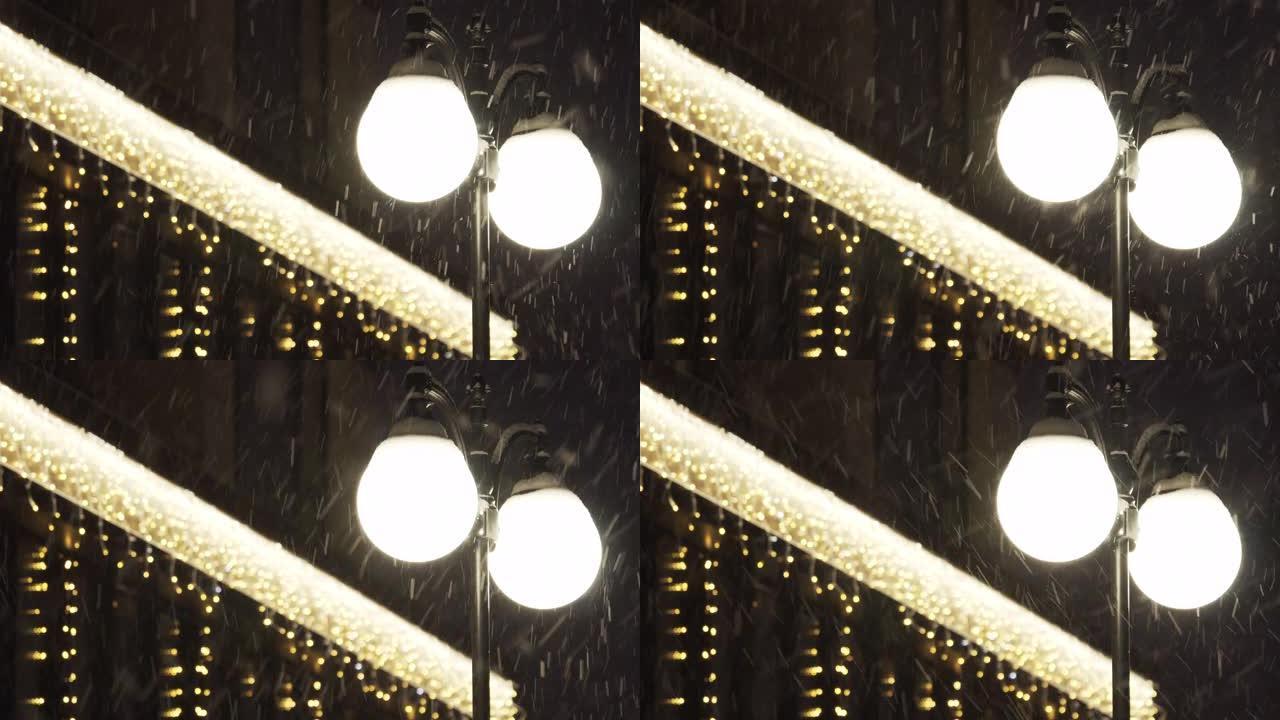 晚上降雪时，城市街道上发光的圆形灯笼。特写。城市景观。外面。雪花落在黑色背景上