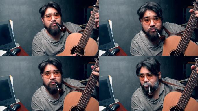 亚洲小胡子男人在家里努力工作时弹吉他放松