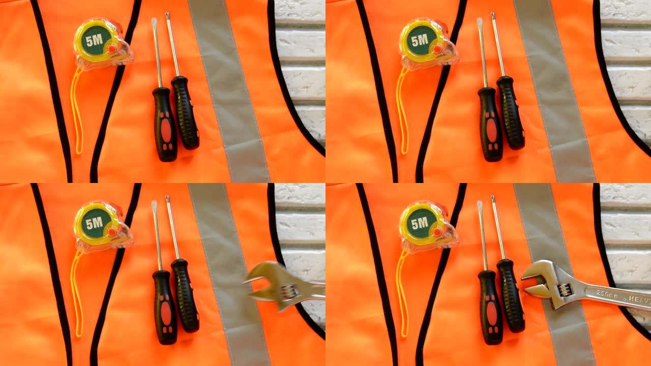 橙色建筑背心上有螺丝刀建筑工具、卷尺、扳手、劳动节概念