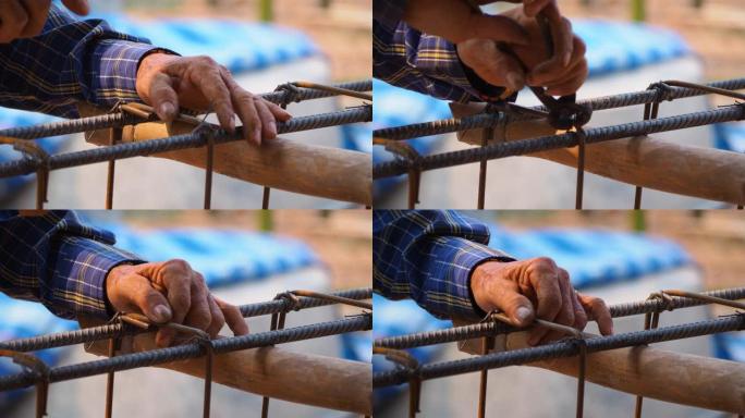 近距离施工工人的手使用钳子工具和铁丝编织金属棒，以在混凝土浇筑之前固定钢筋。建筑施工和行业概念。运动